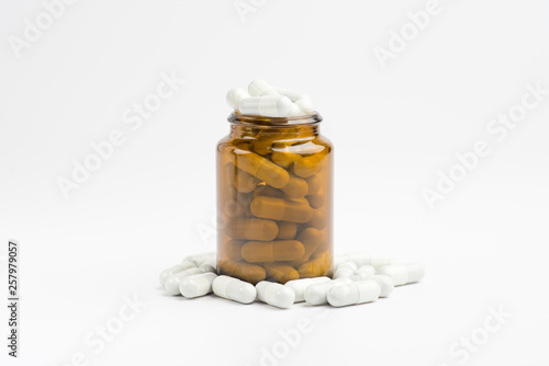 Medicine white pills or tablets drop out of the brown glass bottle on white background.