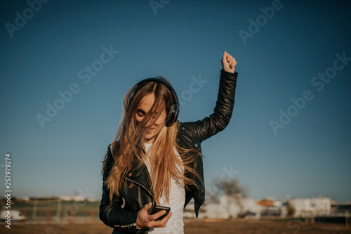 Happy young woman listening music with headphones outdoors