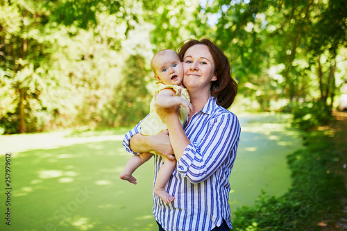 Happy young woman holding her little baby girl outdoors