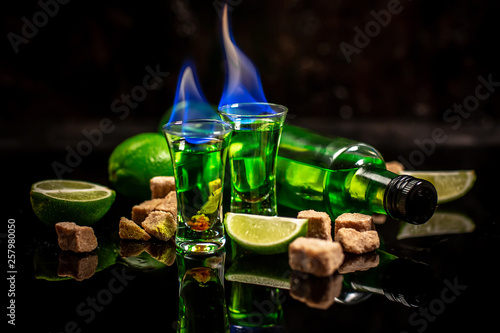 absinthe shots with sugar cubes. absinthe poured into a glass. bottle of absinthe with brown sugar and lime isolated on black background. space for text photo