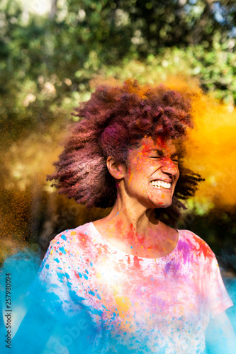 Woman shaking her head, full of colorful powder paint, celebrating Holi, Festival of Colors photo