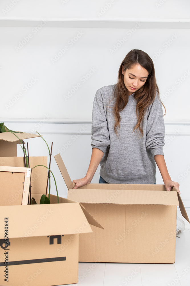 Woman standing in new home with cardboard boxes Woman standing in new home with cardboard boxes