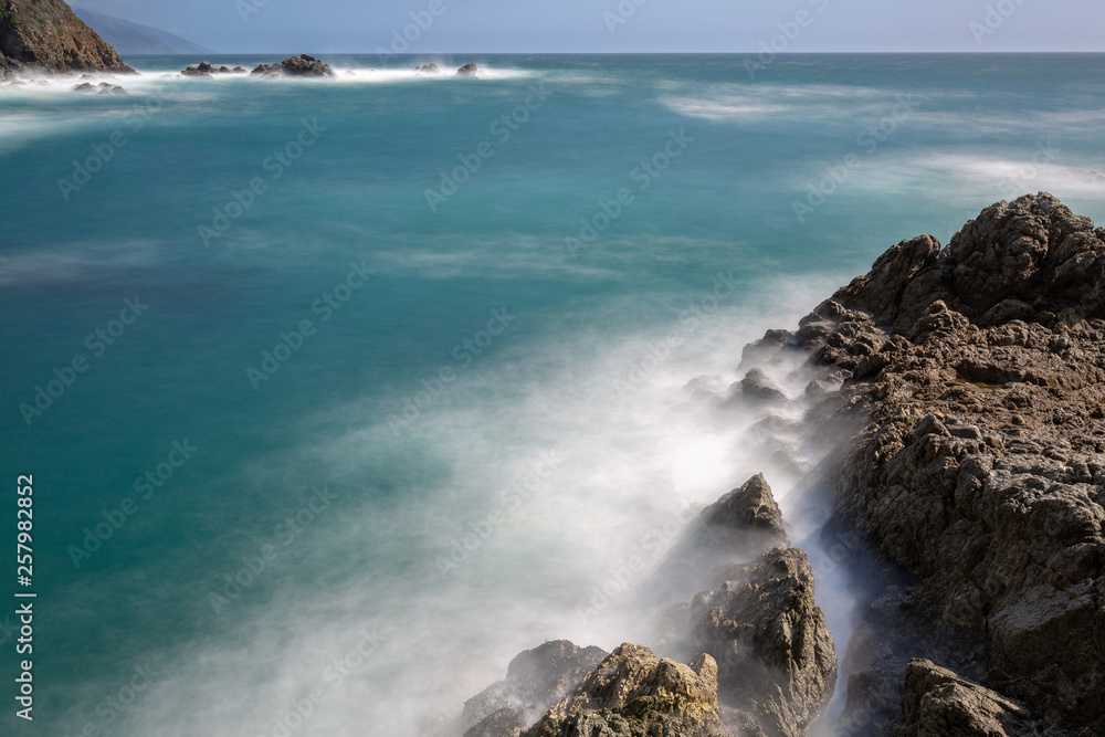 Long exposure of deep blue water, swirling surf, and rocky cliffs of central California Long exposure of deep blue water, swirling surf, and rocky cliffs of central California