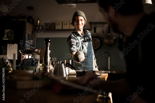 Man with apron standing in his kitchen, showing homemade bread dough photo