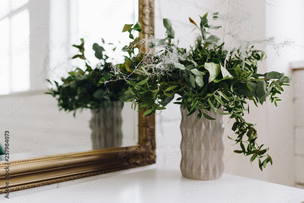 Vase with eucalyptus and other plants on table in front of mirror Vase with eucalyptus and other plants on table in front of mirror