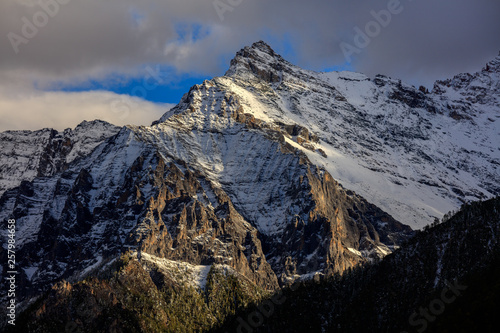 Snow mountains  epic snow covered mountain range - Daocheng Yading Nature Reserve. Ganzi  Garze  Kham Tibetan area of Sichuan Province China. Dramatic lighting during sunset  Clouds and Sky