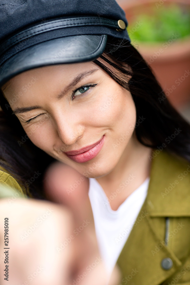 Portrait of a young woman with cap, winking and pointing Portrait of a young woman with cap, winking and pointing
