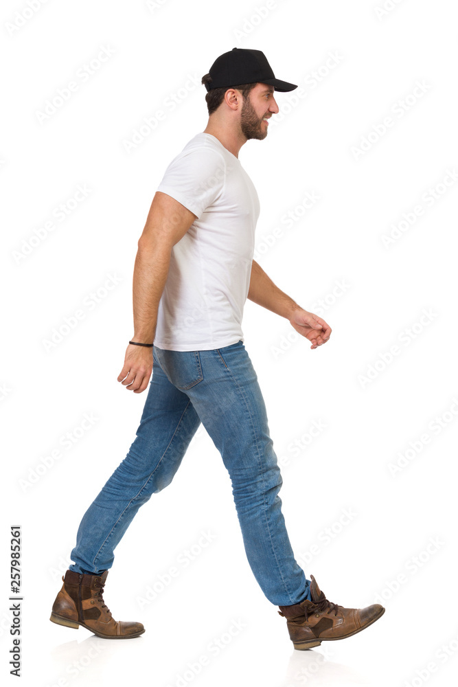 Walking Man In White T-shirt, Jeans, Boots And Black Cap Stock Photo |  Adobe Stock