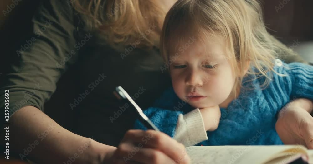Young mother writing and drawing to entertain toddler Young mother writing and drawing to entertain toddler