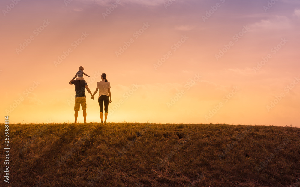 Obraz premium Happy family moment. Parents with their little child watching a beautiful sunset