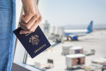 Hand holding USA passport at airport. 