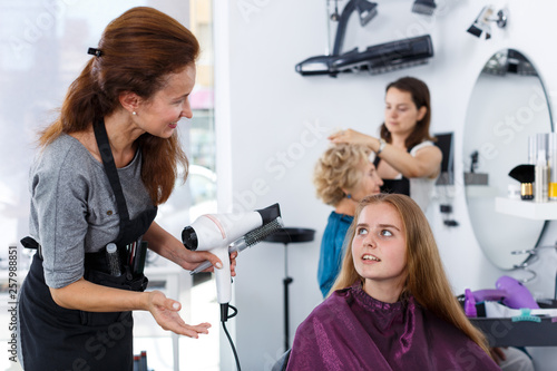 Hairdresser drying hair of teen girl
