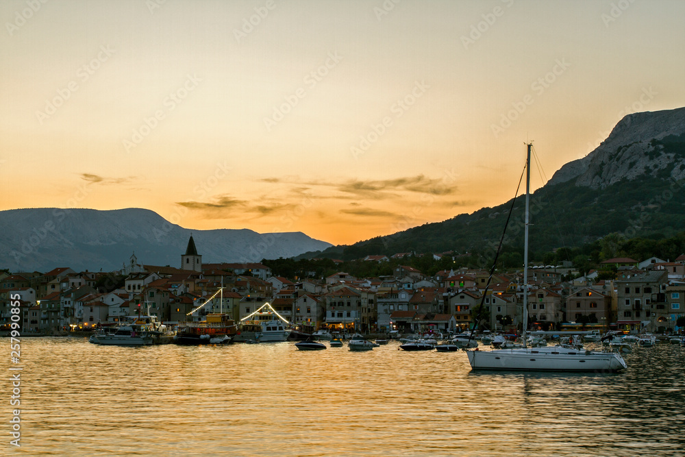 Iandscape at sunset  Small town of Baska . Yacht in the foreground. Island Krk. Adriatic coast, Croatia, Europe. Summer vacation. Relaxation Concept. Beaches of Croatia.
