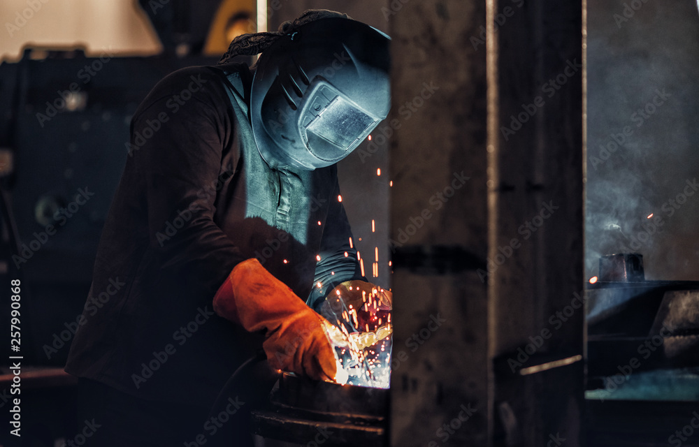 Professional welder performs welding work on metal in protective mask. Industrial worker concept Professional welder performs welding work on metal in protective mask. Industrial worker concept