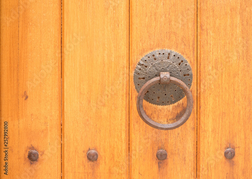 Ancient wooden gate with a door knocker ring close-up 