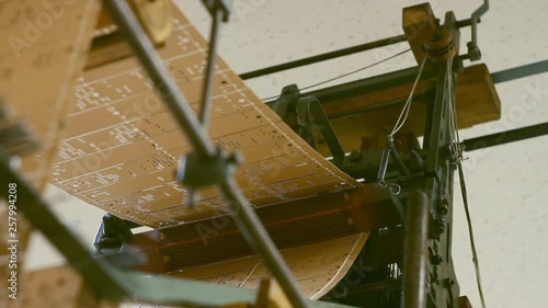 Look at a Jacquard Loom in working action, punching holes on punch card to create a pattern. photo
