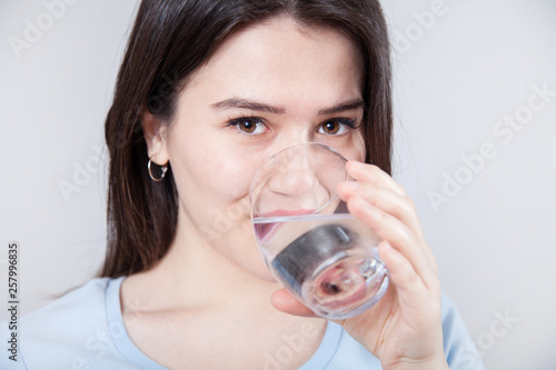 Portrait woman is drinking water on gray background