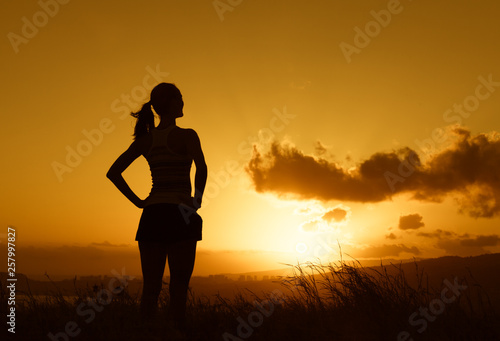 silhouette of girl in the sunset standing on atop a mountain 