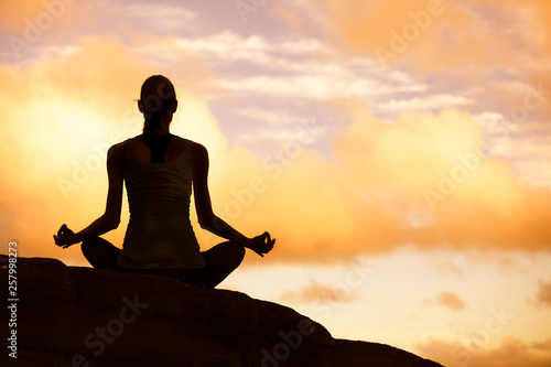 silhouette of woman doing yoga on mountain at sunset