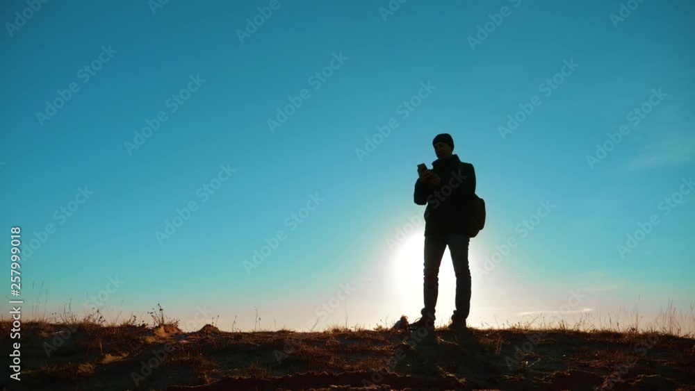 Male man worth it tourist with backpack smartphone navigation sunlight with dog stands on top of a mountain. slow motion video. man silhouette at sunset. hikers adventure and the dog go walking Male man worth it tourist with backpack smartphone navigation sunlight with dog stands on top of a mountain. slow motion video. man silhouette at sunset. hikers adventure and the dog go walking