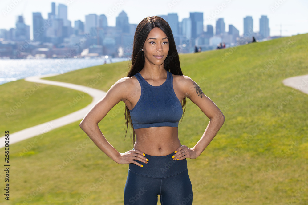 Beautiful woman with long black hair wearing yoga pants and sports bra outside during park workout Beautiful woman with long black hair wearing yoga pants and sports bra outside during park workout