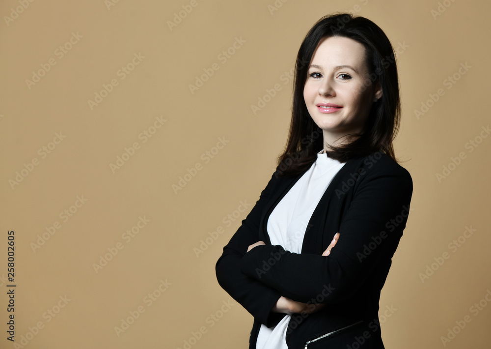 Smiling pretty woman brunette in black cardigan with crossed armson background with free text space Smiling pretty woman brunette in black cardigan with crossed armson background with free text space