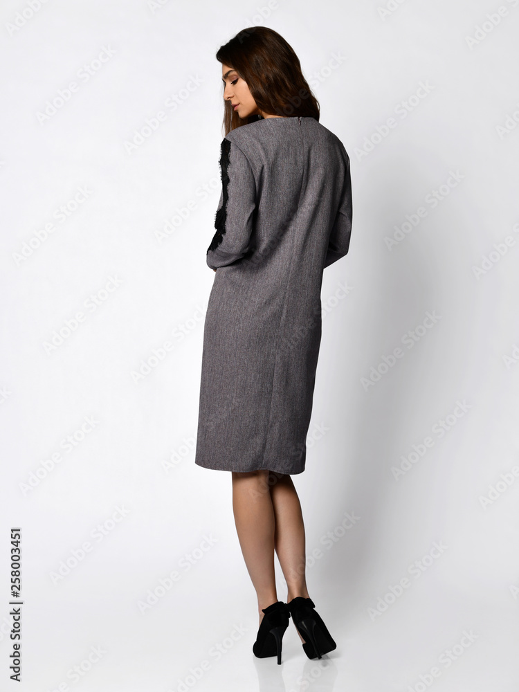 Young beautiful woman posing in new design casual gray spring dress back view on white Young beautiful woman posing in new design casual gray spring dress back view on white