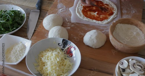 Home made pizza, making process, spreading tomato passata over dough, close-up photo