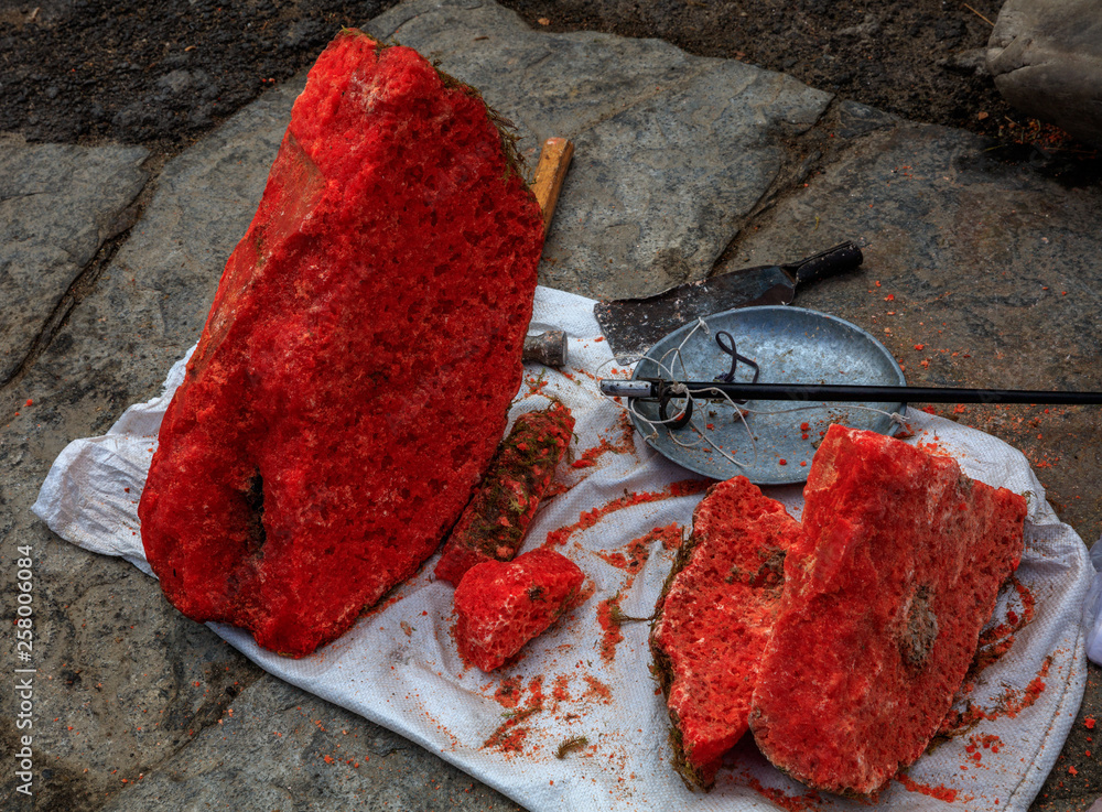 Red Minerals for sale at a small Asian outdoor market. Rare crystals, rock  split using chisel, scale for weighing gemstones for sale. Bright vivid  saturated colors, Red Crystals inside of Rocks. Stock