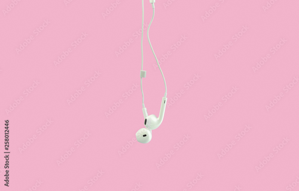 White hanging ear buds headphones isolated on a pink background White hanging ear buds headphones isolated on a pink background