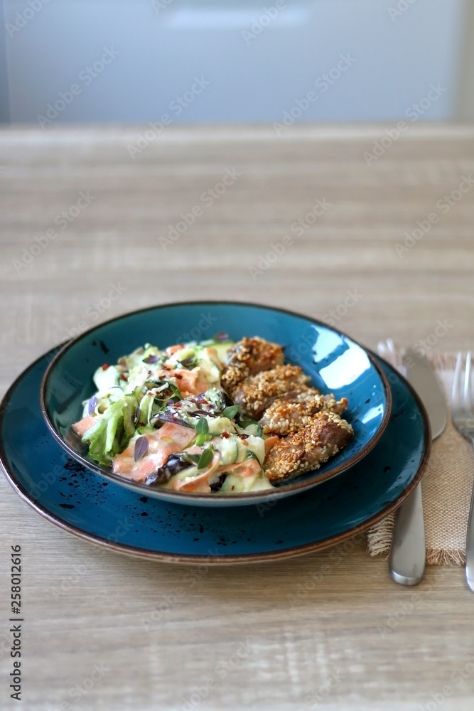 Fried chicken with sesame and zucchini and carrot salad with yoghurt sauce. Selective focus. Fried chicken with sesame and zucchini and carrot salad with yoghurt sauce. Selective focus.