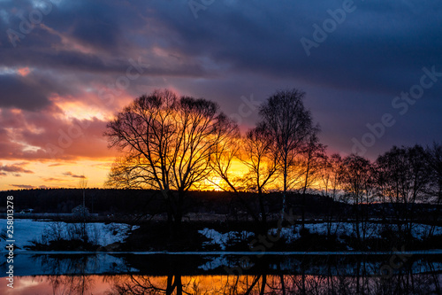Scenic sunset over the trees above the river, colorful sky