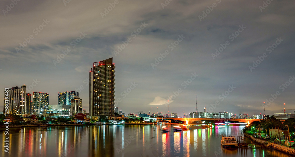 Fototapeta premium Cityscape of modern building near the river in the night. Modern architecture office building. Skyscraper with evening sky. Black and white tone picture. Night photography of riverfront building.
