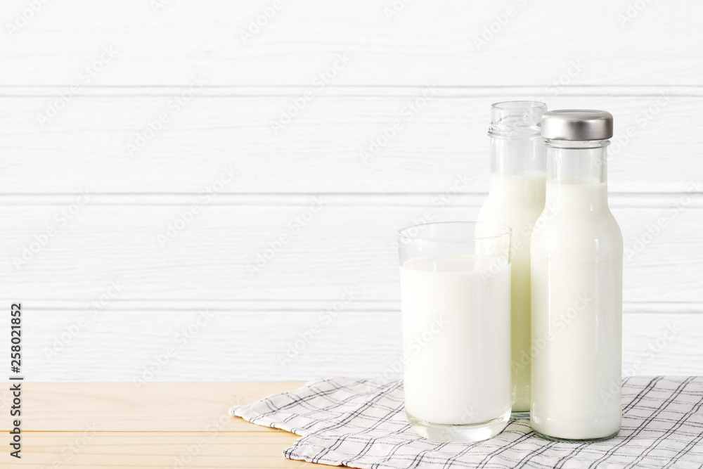 Milk in glass and bottle put on wooden table in white wood wall room. Milk in glass and bottle put on wooden table in white wood wall room.