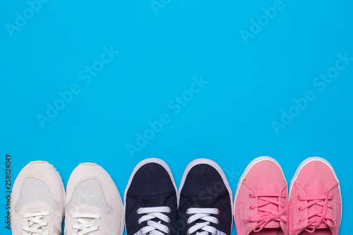 colorful shoes top view. Set of different sneakers on blue background, copy space.