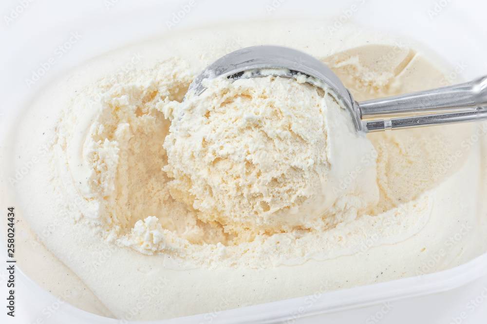 Vanilla ice cream with a scoop in  container as background. Macro. Scooped out ice-cream,  top view.
