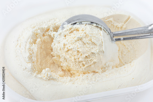 Vanilla ice cream with a scoop in container as background. Macro. Scooped out ice-cream, top view.