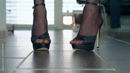 showing elegant plateau stiletto high heels in front of the camera placed on the floor. Presented by a woman in dark stockings.