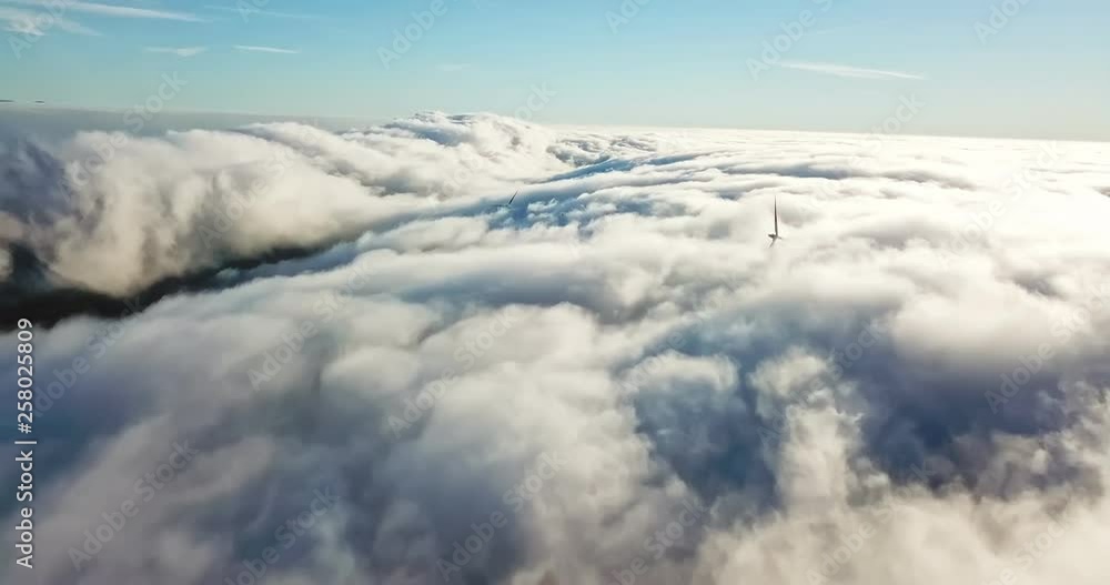 View of a drone above the fog, wind turbines with fog and blue sky View of a drone above the fog, wind turbines with fog and blue sky