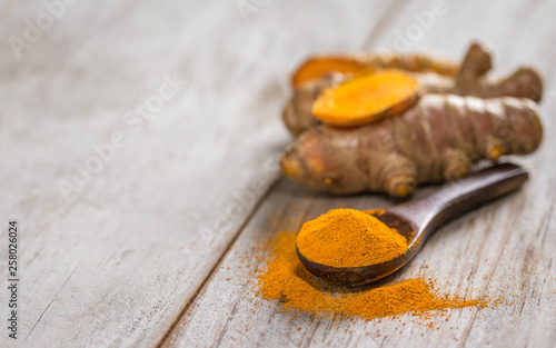 Turmeric powder and roots on wooden background, asian herb for medication