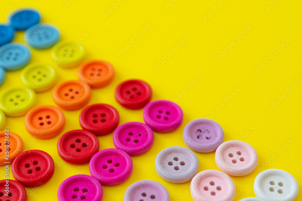 Multi-colored buttons on a yellow background. Button rainbow for clothes. Copy space Multi-colored buttons on a yellow background. Button rainbow for clothes. Copy space