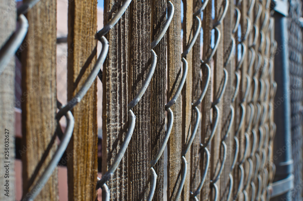 A textured pattern of the wooden slats in the chain linked fence. A textured pattern of the wooden slats in the chain linked fence.
