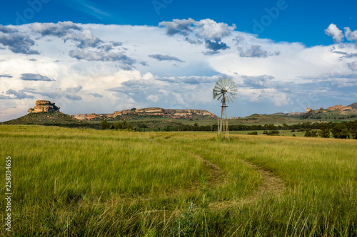 Farm scene with a wind pump and sandstone mountains