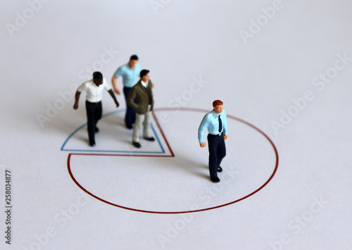 Miniature people standing on a circle graph.