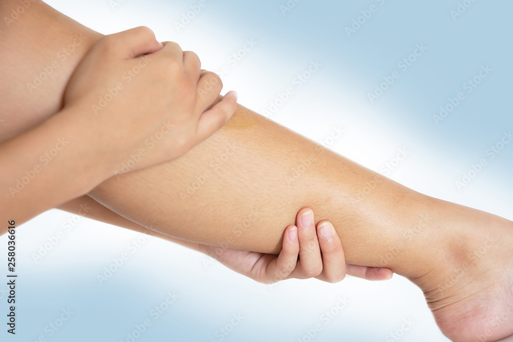 young woman massaging her painful heel. Isolated on white and blue background young woman massaging her painful heel. Isolated on white and blue background