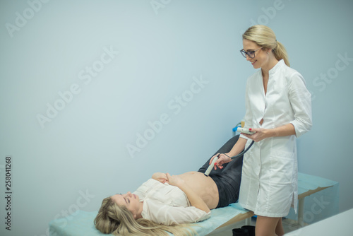 A gynecologist examines a pregnant woman. Fetal doppler heart auscultation. Patient at doctor office.