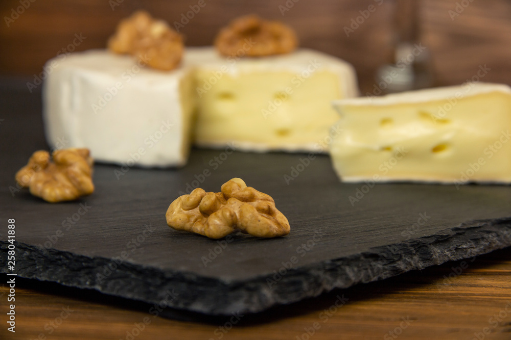 Camembert chopped in a dark background with nuts