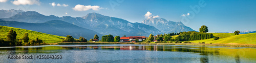 Fotografia, Obraz Panoramic bavarian landscape with small village by a lake, the alps behind, Allg