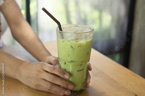Iced green tea in woman hand.