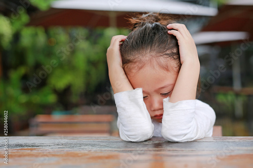 фотографія Close-up of adorable little Asian child girl expressed disappointment or displeasure on the wood table